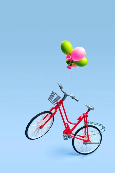 青い背景にハンドルバーに縛られたいくつかの風船で自転車を飛んでいます バレンタインデーとロマンチックなコンセプト輸送エコ愛 — ストック写真
