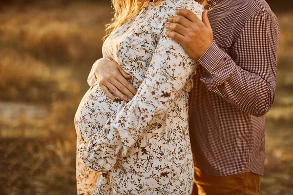 无法辨认的夫妻 未来的父母 未来母亲的手紧紧抓住怀孕的大肚子 丈夫拥抱怀孕的妻子 身穿白色棉衣的白人妇女 — 图库照片