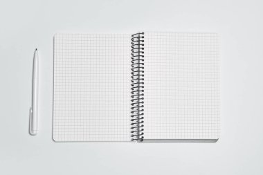 Üst görünüm, boş defter ve beyaz arkaplan üzerindeki kalem.