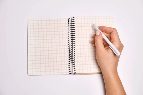 女性の手のペンを保持し 薄い白の背景に 空白の白いページとスパイラルノートブックを開きます 企画コンセプト — ストック写真