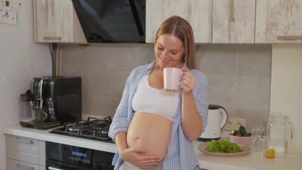 人与健康饮食概念 怀孕妇女站在家中厨房用热饮放松食欲 — 图库视频影像