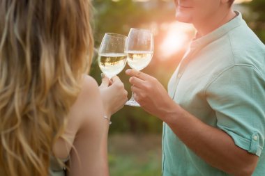 Dışarıda kadeh kaldıran romantik bir çift. Güzel bir kadın erkeğiyle kadeh tokuşturuyor..