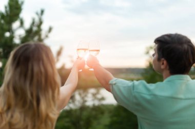 Dışarıda kadeh kaldıran romantik bir çift. Güzel bir kadın erkeğiyle kadeh tokuşturuyor..