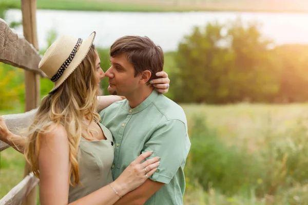 田舎の日没で夏の牧草地で男が歩いてキスをしている若い女性のショットを閉じます 散歩を楽しむカップル — ストック写真