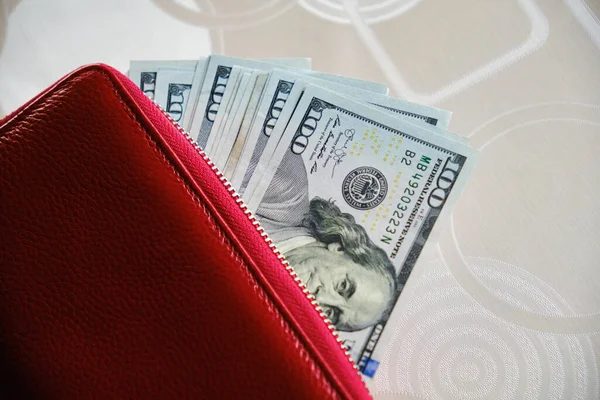 Un portefeuille avec des billets de cent dollars qui en sortent. — Photo