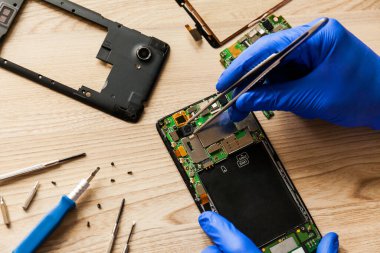 The technician repairing the smartphones motherboard in the workshop on the table. Concept of mobile phone, electronic, upgrade and technology.