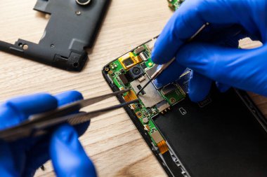 The technician repairing the smartphones motherboard in the workshop on the table. Concept of mobile phone, electronic, upgrade and technology.