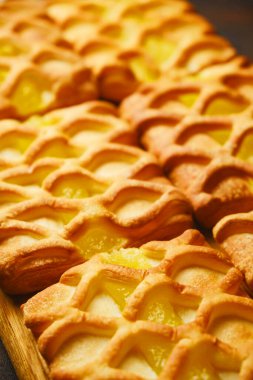 Armut ve kireç reçelli taze poğaçalı mini turtaların arka planlarını kapatın. Koyu siyah ve kırmızı desenli armut ve limon dilimleriyle donatılmış arka planda, yukarıdan, yassı düz.