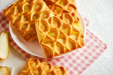 Armut ve limon reçelli puf börekleri kareli bir peçetede beyaz bir tabakta taze armut ve limon dilimleri ile dolduruluyor, yukarıdan yatay görüş, düz kaplama.