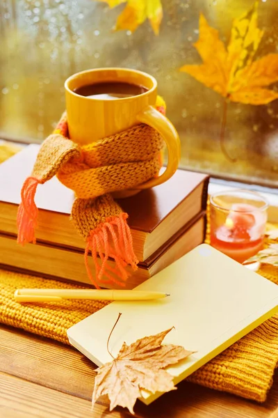 Creative mood. Cup of tea, autumn leaves, books, notebook and red knitted plaid on wooden table. Cozy autumn composition with mock up notebook. fall, thanksgiving day concept.