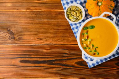 Kremalı ev yapımı balkabağı çorbası, kabak tohumu ve fesleğen kırsal ahşap arka planda, seçici odak, kopyalama alanı