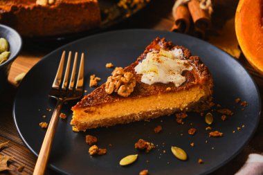 Şükran Günü için siyah tabakta çırpılmış kremayla süslenmiş ev yapımı balkabaklı cheesecake. Tonu. seçici odak