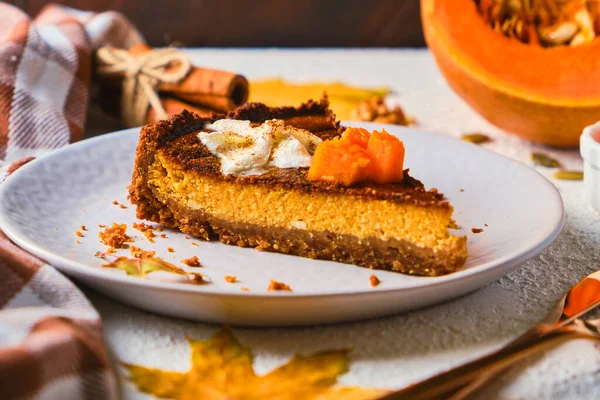 Homemade pumpkin cheesecake decorated with whipped cream on gray plate. selective focus, white textured background