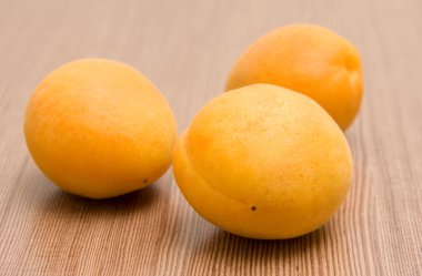 ahşap yüzey üzerinde üç turuncu kayısı