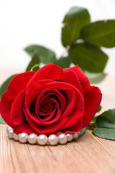 Rosa roja y perlas en mesa de madera —  Fotos de Stock