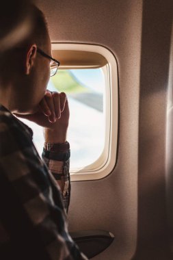 Bir adam düşünceli bir şekilde uçağın penceresinden dışarı bakar. Hayatını değiştirmek için önemli bir karar.
