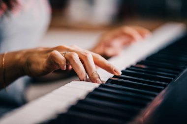 Kadın bir piyanistin eli zarif bir şekilde piyano çalarken.