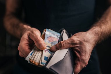 Adamın biri cüzdanına bir tomar para koyuyor.