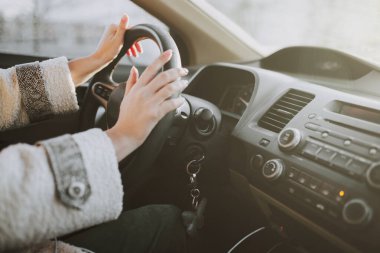 Bir kadının elleri arabanın direksiyonundaydı. Renkli film tahılları sürüyordu.