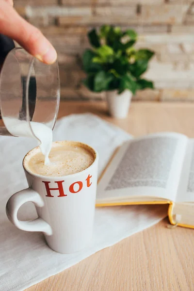 浓重的牛奶泡在装咖啡的杯子里 早餐时阅读你最喜欢的书 — 图库照片