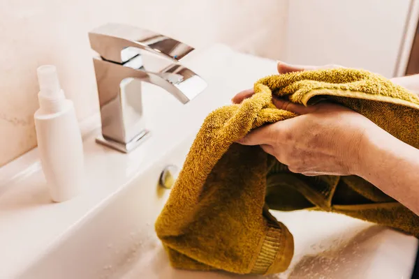 Kadın, ellerini yumuşak bir havluyla yıkadıktan sonra siler. Kişisel temizlik.