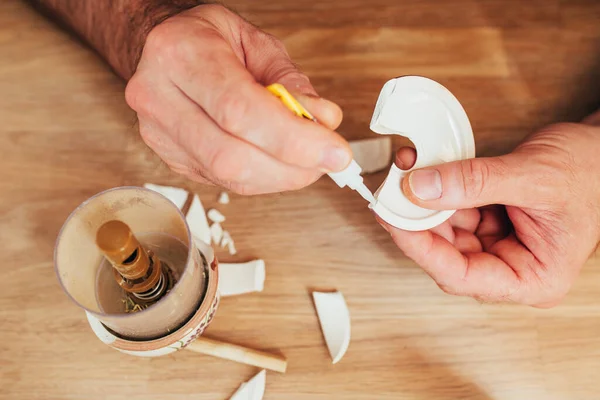 A man sequentially glues pieces of broken dishes - the task is to restore broken ceramics