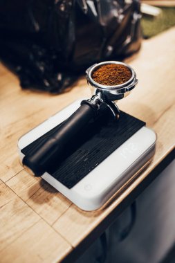 Profesyonel barista terazide kahve tutacağı ile tartılır. Espresso makinesinde baskı altında kahve demler.