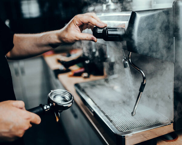 Hands Professional barista at work by an espresso machine - thick steam in a coffee shop