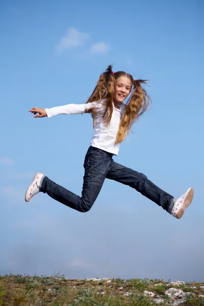 Little girl happily jumping against the blue sky — Stock Photo, Image