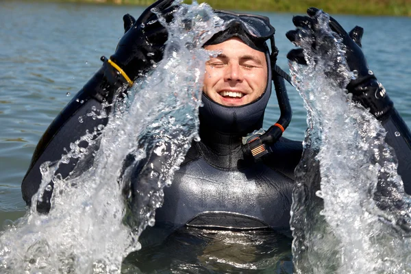 Buceador en traje de buceo con salpicaduras de saltar fuera del agua y jadear por aire — Foto de Stock