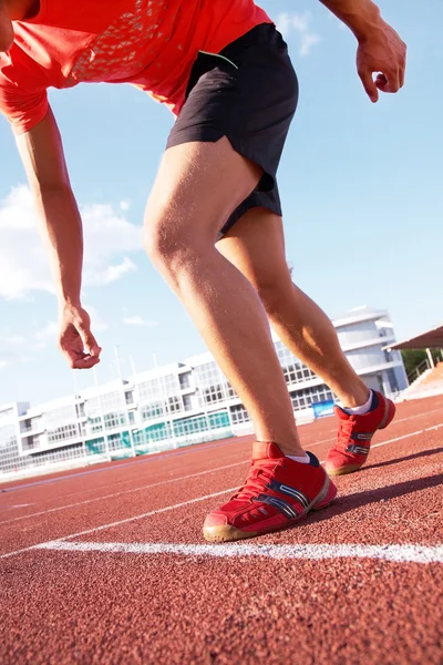 Jonge gespierde atleet loopt op het stadion achtergrond van de blauwe hemel — Stockfoto