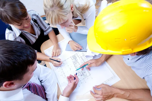 Voldoen aan het team van ingenieurs op een bouwproject aan de tafel — Stockfoto