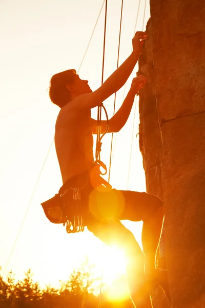 Silhouette dell'uomo che si arrampica su una scogliera — Foto Stock