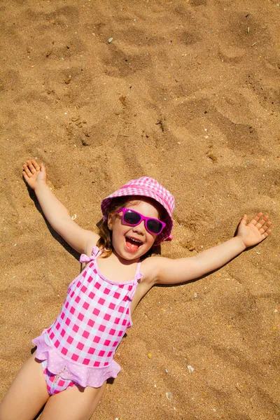Маленькая девочка лежит на песчаном пляже — стоковое фото