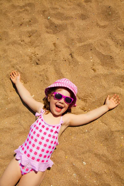 Liten flicka ligger på sandstranden — Stockfoto