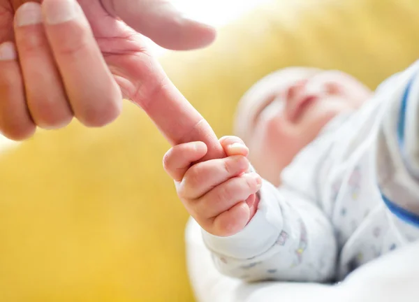 Baby holding dad's finger. — Stock Photo, Image
