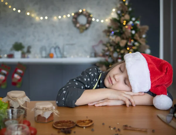 サンタの帽子の女の子はクリスマス前に台所で眠ってしまった — ストック写真