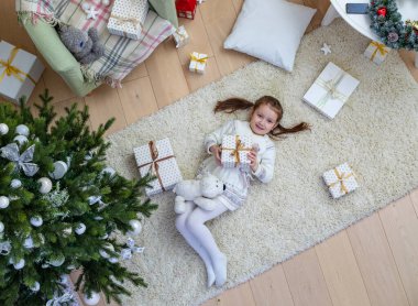 Halı üzerinde hediyeler Noel ağacının altında yatan mutlu küçük kız. Yukarıdan görüntülemek