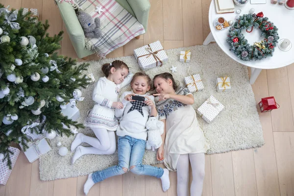 3人の幸せな少女はクリスマスツリーの下にカーペットの上の贈り物で横たわっていた 上からの眺め — ストック写真