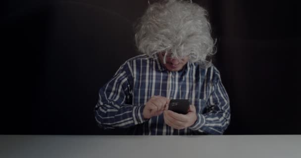 一位年长的典型的潮人弯腰在他的智能手机上输入短信 黑色背景 — 图库视频影像
