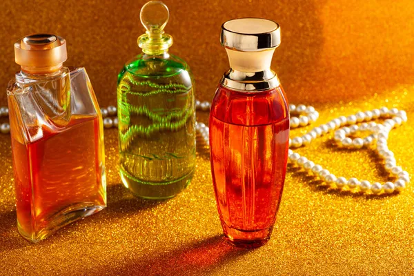 Naranja Verde Frascos Perfume Collar Perlas Superficie Brillante Oro —  Fotos de Stock