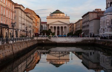 Gün batımında Trieste 'deki Gran Canale manzarası. Aziz Antonio Kilisesi Thaumaturgo Büyük Kanal 'ın suyuna yansıdı. 