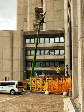 İki inşaat işçisi şantiyede vinçle çalışıyor. 