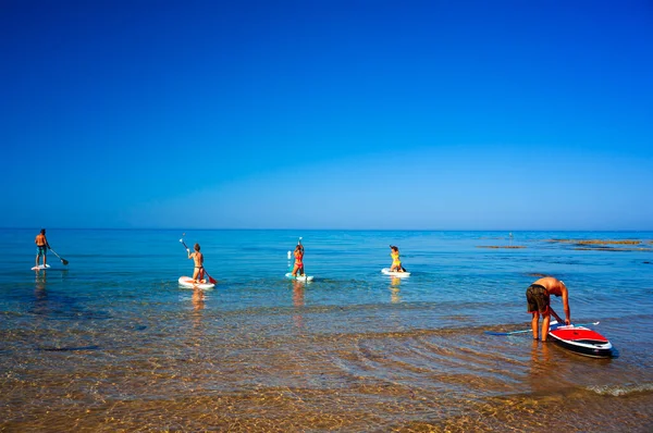 Realmonte, İtalya - 23 Temmuz, ayağa kalkın. Neşeli bir grup arkadaş, 23 Temmuz 2021 'de Realmonte sahilinde güneşli bir sabah Akdeniz' de SUP yönetim kurulunu eğitiyorlar.