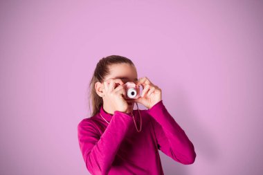 Küçük Kız Fotoğraf Çekiyor Pembe arka planda Oyuncak Fotoğraf Kamerası Kullanıyor