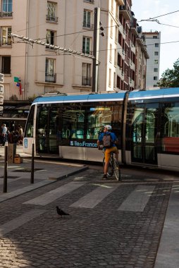 Paris, France - July, 13: The cyclist stopped at the pedestrian crossing is waiting for the passage of the tram of the 13th arrondissement on July 13, 2022