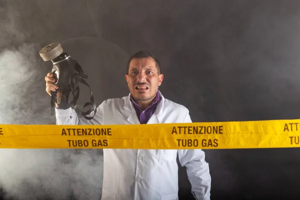 A medical engineer with an antigas mask on his hand directs the emergency in the chaos during the gas leaks. On the yellow tape the written notice \