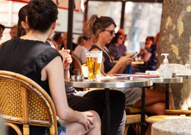 Paris, Fransa - 15 Temmuz: 15 Temmuz 2022 'de bir yaz barında bir masada oturan ve bira içen bir grup genç