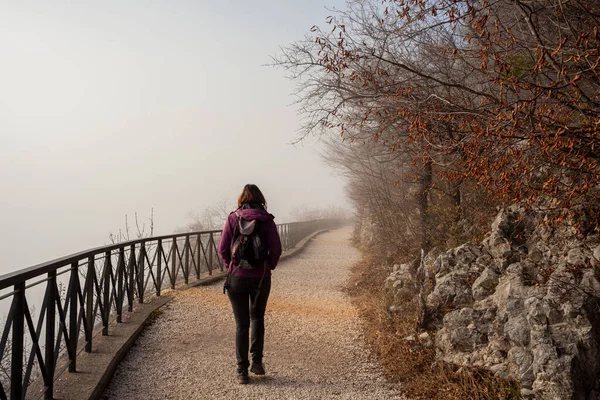 Back view of a Woman walking alone on rural misty path called Napoleonica, Trieste