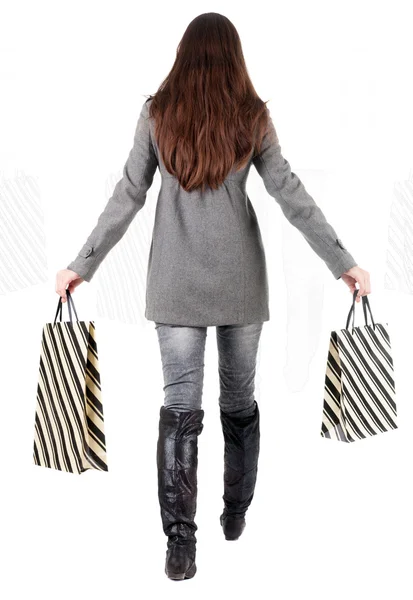 Back view of going woman in jacket with shopping bags — Stock Photo, Image